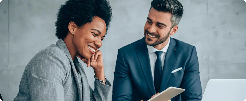 Male and female business team members smile as they talk to each other.